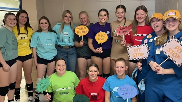 Un grupo de alumnas de la Kate Andrews High School sostiene carteles coloridos con mensajes humorísticos y alentadores.