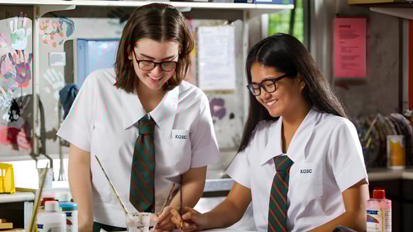 Dos estudiantes en uniformes escolares están juntas y sonriendo en el aula del Kelvin Grove State College.