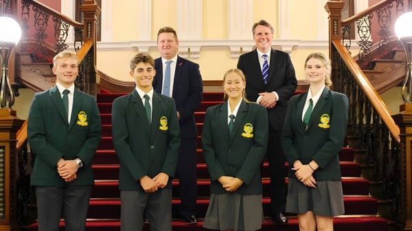 Un grupo de estudiantes y dos adultos están en la gran escalera de la Kenmore State High School.