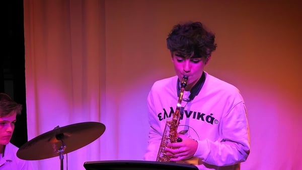 Una persona toca el saxofón en el escenario frente a luces de colores en Kensington Park School.
