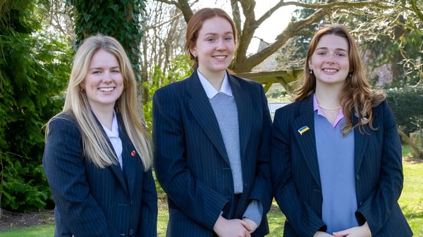 Tres alumnas en uniformes del Kent College Pembury están juntas y sonríen en el bosque.