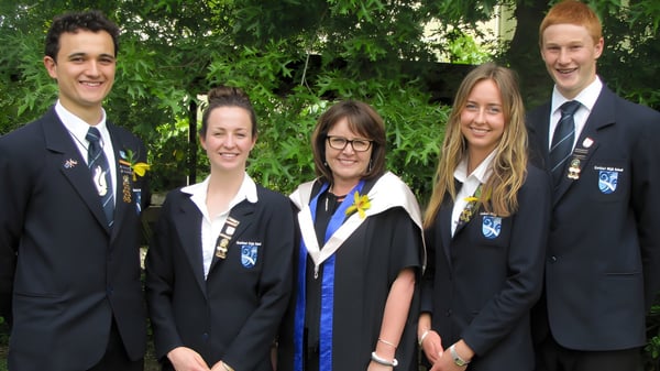 Un grupo de cinco personas en togas académicas está en el terreno de la Kerikeri High School al aire libre.