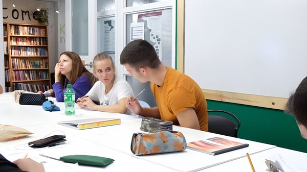 Tres estudiantes están sentados en una mesa en la biblioteca y aprenden juntos en el campus de la Keystone School.
