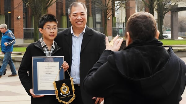 Un estudiante de la Killarney Secondary School recibe un premio al aire libre de un hombre mayor.