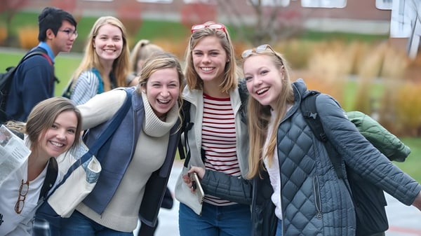 Un grupo de estudiantes está afuera en invierno frente a edificios de ladrillo en el campus de la Kimball Union Academy.