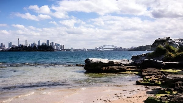 Vista del panorama costero con rocas y agua frente al horizonte de Sydney en el campus de Kincoppal-Rose Bay.