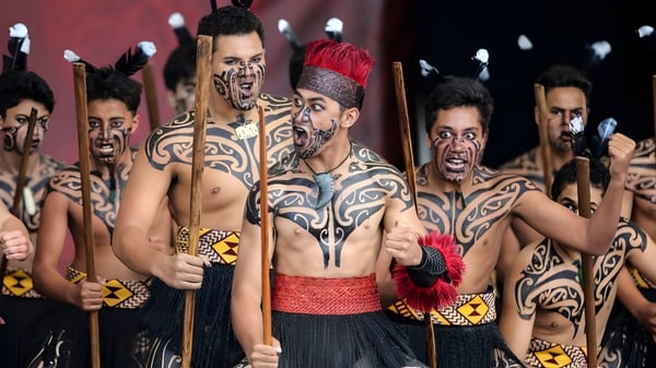 Un grupo con complejas pinturas corporales y vestimenta tradicional en una performance de arte en el King's College.