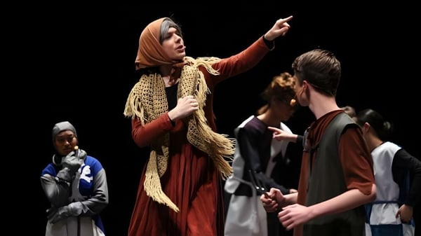 Una mujer con un vestido rojo gesticula durante una discusión con otra persona en el campus del King's College.