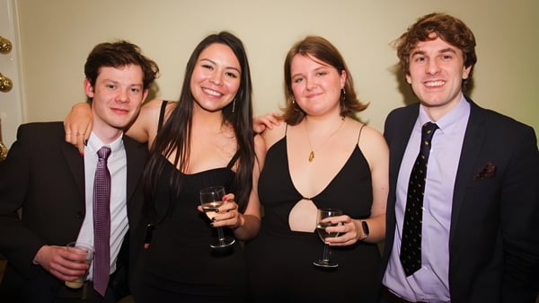 Cuatro personas están juntas en un evento en el King's College y llevan ropa formal.