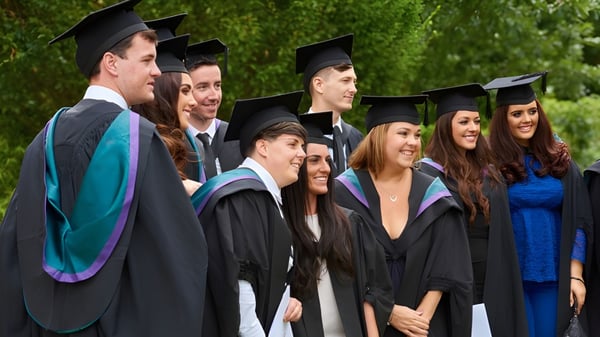 Las graduadas y graduados de la King’s-Edgehill School están juntos al aire libre frente a un fondo verde.