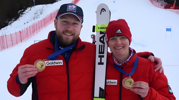 Dos personas de la King's School muestran orgullosamente sus medallas de oro en un evento invernal.