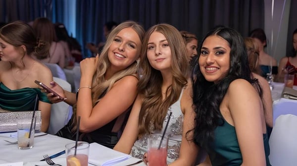Un grupo de alumnas de la Kingsley School posan en un evento formal frente a una cortina.