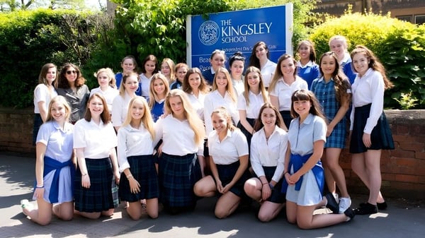 Un grupo de alumnas posan frente al letrero de la Kingsley School rodeadas de árboles y áreas verdes.