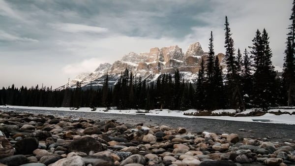 Paisaje invernal nevado con un lecho de río y montañas cerca de la Kingston Secondary School.