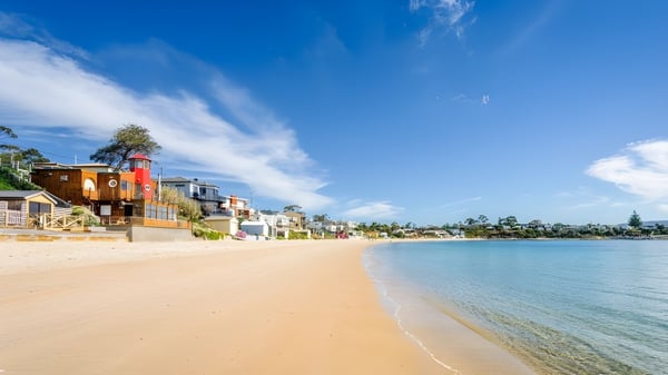 Casas de playa coloridas en la costa cerca de la Kingston High School bajo un cielo despejado.