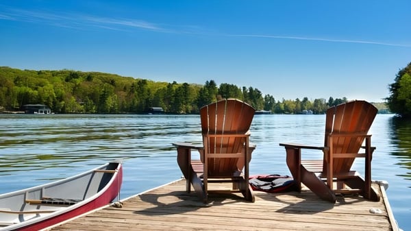 Dos sillas de madera están en un muelle junto al lago en el terreno de la Kingsville District High School.