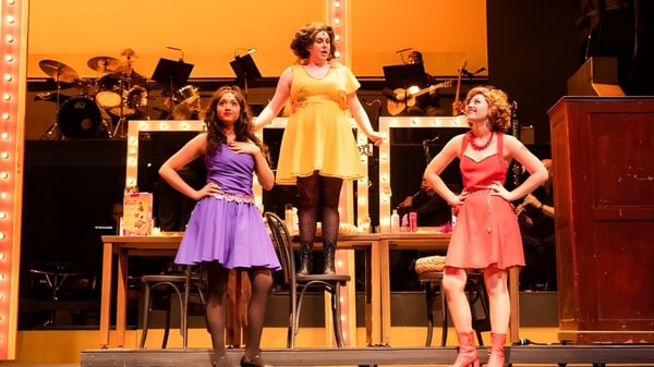 Tres estudiantes de Kingswood Oxford actúan en el escenario con una banda de fondo.