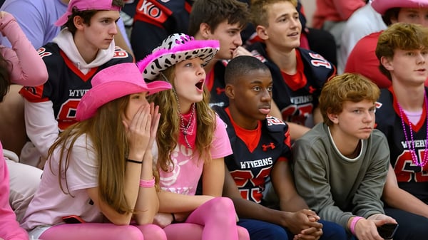 Un grupo de aficionados apoya activamente a su equipo en un evento deportivo en el campus de Kingswood Oxford.