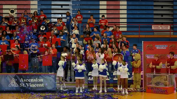 Un grupo de estudiantes en uniformes rojos y azules está en el gimnasio de la Kokomo-Center Township Consolidated School Corporation.