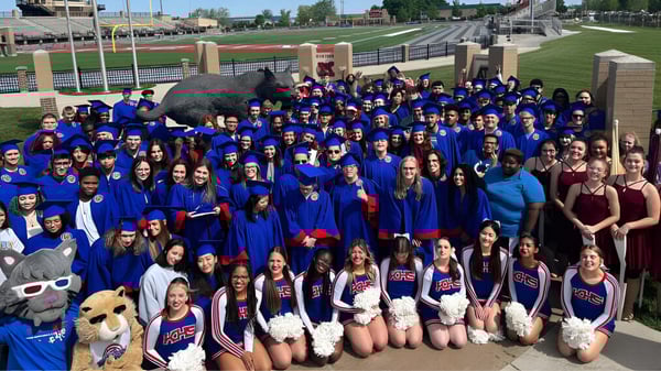 Un grupo de alumnas y alumnos de la Kokomo-Center Township Consolidated School Corporation está frente a un estadio deportivo.