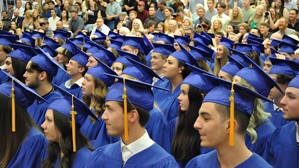 Un gran grupo de graduadas y graduados en togas azules está sentado en la ceremonia de graduación de la Kootenay River Secondary.