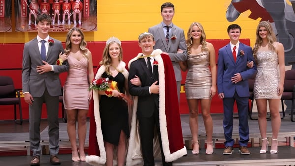 Un grupo de personas vestidas de manera festiva posan frente a decoraciones chinas en la Kuemper Catholic High School.