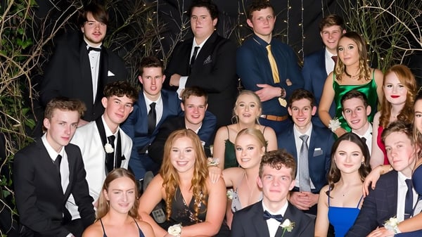 Un grupo de estudiantes del Kuranui College en ropa formal posan afuera frente a árboles.