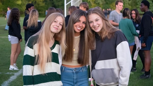 Un grupo de estudiantes con cabello largo está riendo en un campo en el terreno de la La Lumiere School.