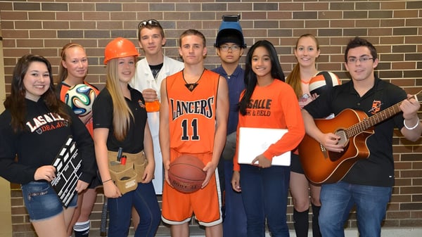 Un grupo de estudiantes de La Salle Secondary School posan frente a una pared de ladrillo.