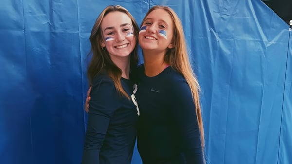 Dos alumnas de Lacey Township High School se abrazan frente a un fondo azul y sonríen.
