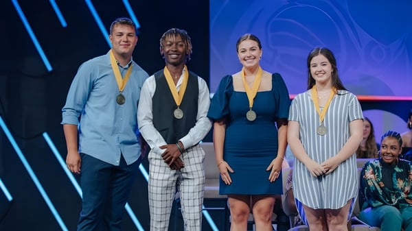 Cuatro personas en ropa formal en el escenario de Lafayette Christian Academy con premios en la mano.