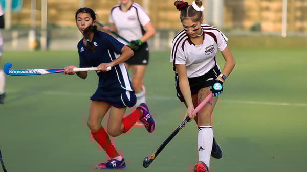 Dos estudiantes de la Lake Cowichan Secondary School juegan un partido de hockey sobre césped en un campo deportivo.
