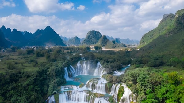 Una impresionante cascada frente a colinas verdes y montañas bajo un cielo azul en el terreno de la Lakefield College School.