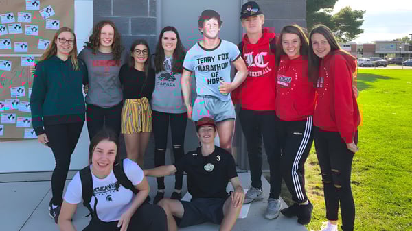 Un grupo de estudiantes está frente al edificio del Lambton Central Collegiate & Vocational School y posando para una foto.