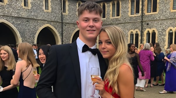 Una pareja joven está frente al edificio histórico con arcos y arquitectura decorada en el campus del Lancing College.