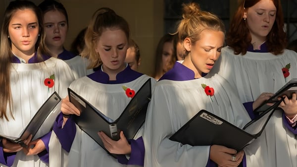 Un grupo de estudiantes en túnicas blancas con libros en el interior del campus del Lancing College.