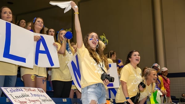 Un grupo de estudiantes de Lander University lleva camisetas amarillas y anima en un evento deportivo.
