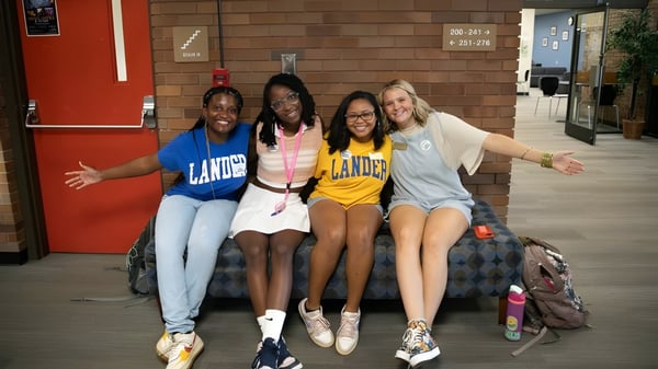 Un grupo de cuatro estudiantes está junto y sonríe en el campus de Lander University.