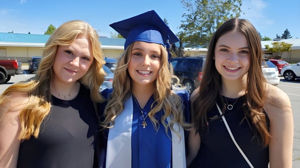 Tres estudiantes de la Langley Fundamental Middle and Secondary School están sonriendo juntas en una fiesta de graduación al aire libre.