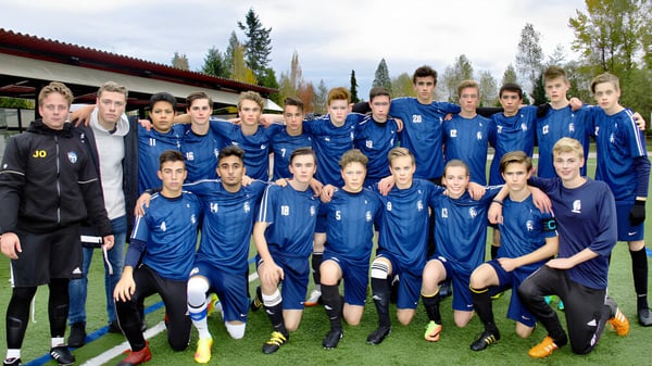 Un grupo de estudiantes femeninas de la Langley Fundamental Middle and Secondary School posa juntas en camisetas azules en un campo de juego.