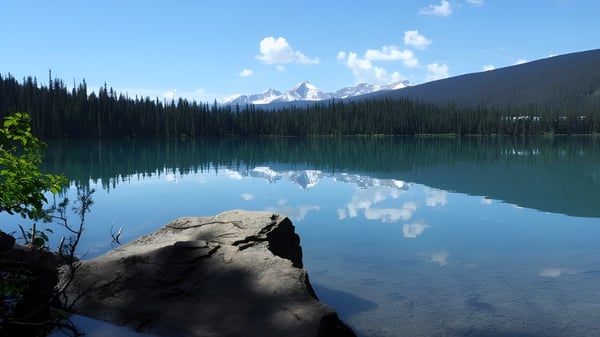 Un claro lago de montaña con el reflejo de las cumbres nevadas en el fondo de la Langley Secondary School.