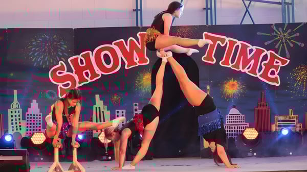Un grupo de performers está en el escenario con el letrero Show Time de fondo en el campus del Largy College.