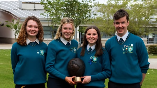 Cuatro estudiantes en uniformes escolares están juntos frente a un edificio en el campus del Largy College.