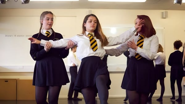 Tres alumnas de la Larkmead School están juntas en el pasillo escolar con sus uniformes.