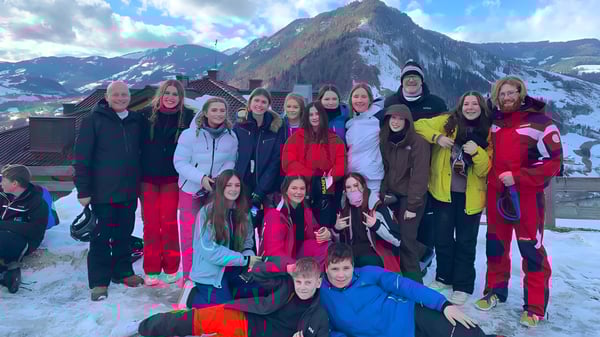 Un grupo de alumnos de la Larkmead School posan frente a un impresionante paisaje montañoso cubierto de nieve.