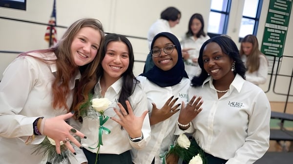 Un grupo de estudiantes sonrientes en uniformes blancos posan juntas en la Laurel School.