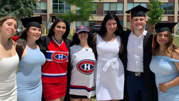 Un grupo de estudiantes de la LaurenHill Academy en ropa de graduación y camisetas de hockey está frente a un edificio con árboles.