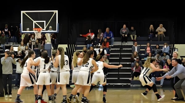 Estudiantes juegan un partido de baloncesto en la cancha de la Laurens Academy frente a espectadores en las gradas.