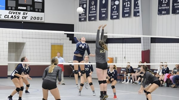 Estudiantes de la Laurens Academy juegan un partido de voleibol en un gimnasio con pancartas de la clase de 2005.
