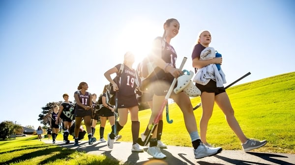 Un grupo de alumnos y alumnas de la Lawrence Academy pasea juntos por un prado verde.